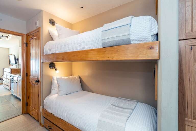 There are bunk beds in the hallway between the living room and main bedroom.