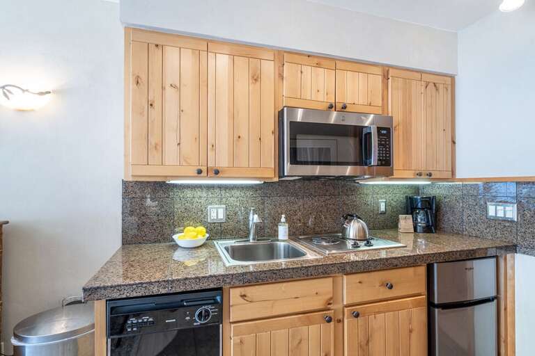 The condo has a kitchenette with a mini fridge, cooktop, microwave, dishwasher and coffee maker.