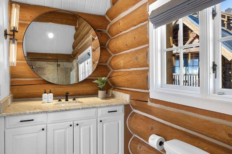 This bathroom is designed with a classic log cabin aesthetic, blending rustic charm with modern comfort