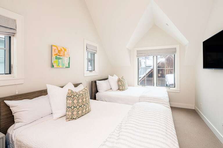 The third level guest bedroom, features two queen beds with a flat screen TV bright light and ample storing space.