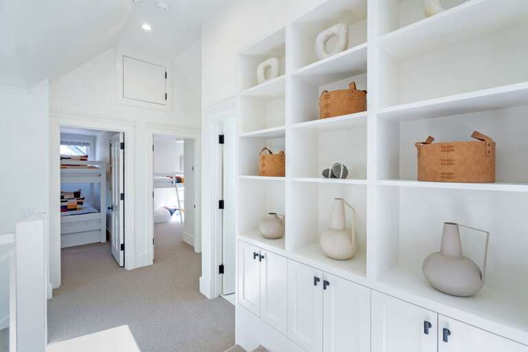 The third floor includes a media room with comfortable bean bag seating, a shared bathroom with a step-in shower, a desk area, and two bunk rooms.