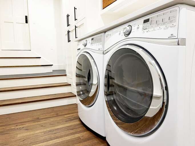 The laundry room features a industrial size front loading washer and dryer.