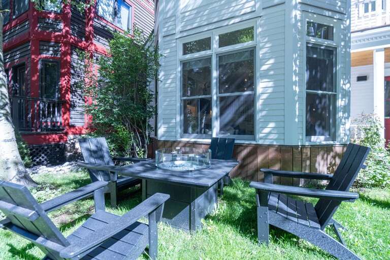 The outdoor seating area has four comfortable adirondack chairs and a gas fire pit.