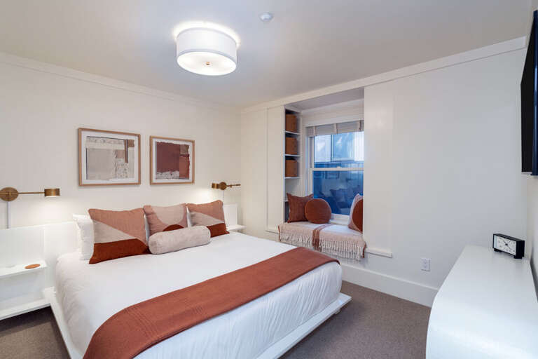 Tucked beside the second-floor landing, this dreamy guest room features a California King bed and a cozy bay window nook.