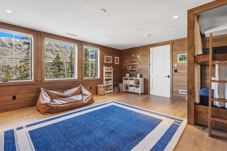 This expansive bunk room offers stunning mountain views and generous additional storage space beneath the beds, combining functionality with breathtaking scenery.