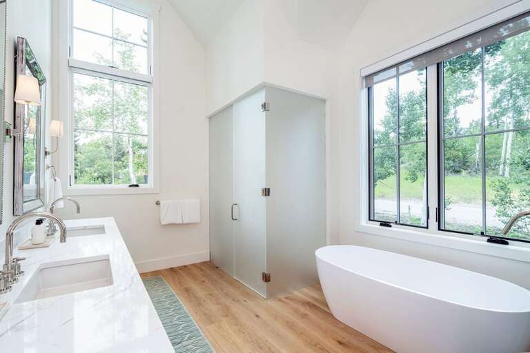 Primary en suite bathroom with a double vanity and private glass enclosed lavatory. Huge soaking tub for relaxing after a fun day.