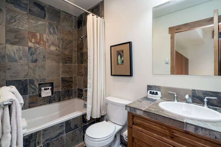 Guest room One features an ensuite bathroom with a tub/shower combo and single vanity.