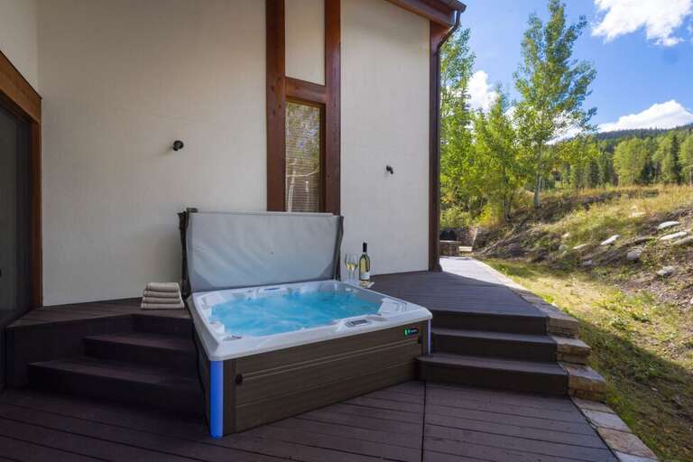 The hot tub, located off the living area, offers a relaxing spot with views of the surrounding forest and steps from Sundancer ski run.