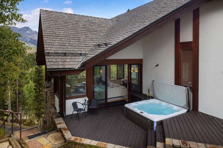 The hot tub, located off the living area, offers a relaxing spot with views of the surrounding forest and steps from Sundancer ski run.