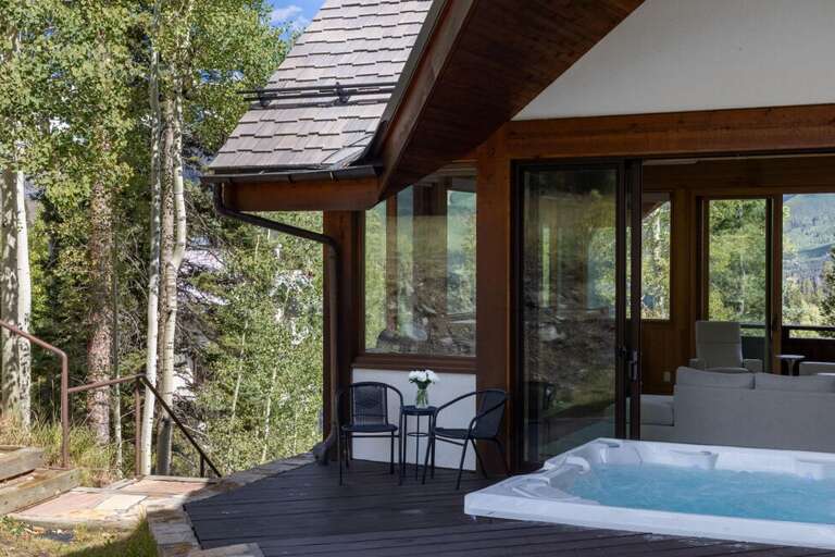 The hot tub, located off the living area, offers a relaxing spot with views of the surrounding forest and steps from Sundancer ski run.