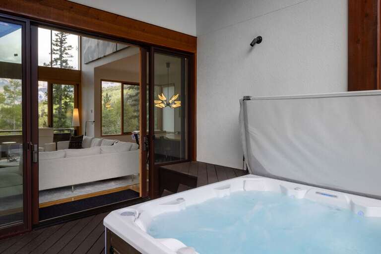 The hot tub, located off the living area, offers a relaxing spot with views of the surrounding forest and steps from Sundancer ski run.
