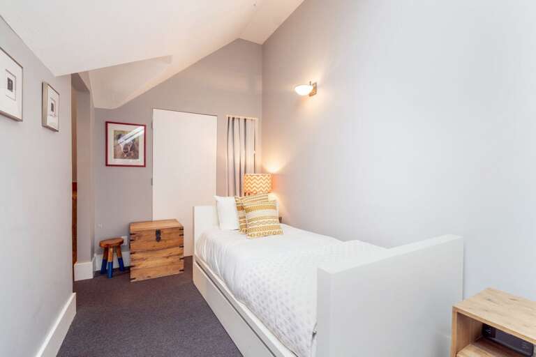 The top floor features a unique treehouse-style sleeping area with three single beds, creating a fun and cozy retreat for kids or additional guests
