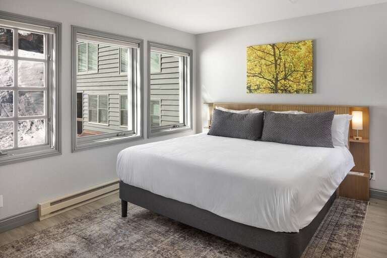 Spacious and inviting primary bedroom with a king bed, stunning slope views, and a private ensuite bathroom.