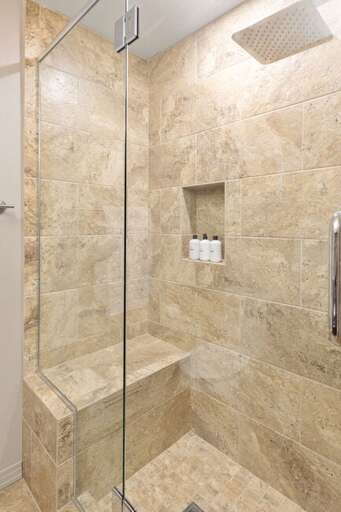 A spacious step-in shower with a rains shower head and plenty of space.