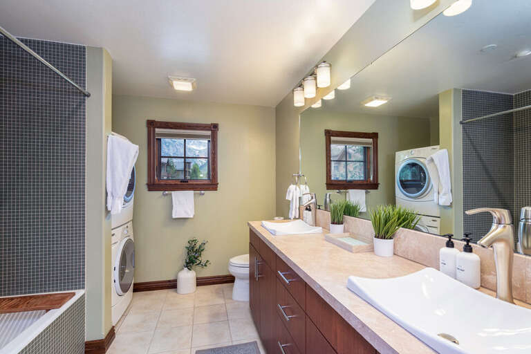 Shared Bathroom for Guest rooms features a large step-in shower bathtub combo, double vanity as well as the stackable washer and dryer.