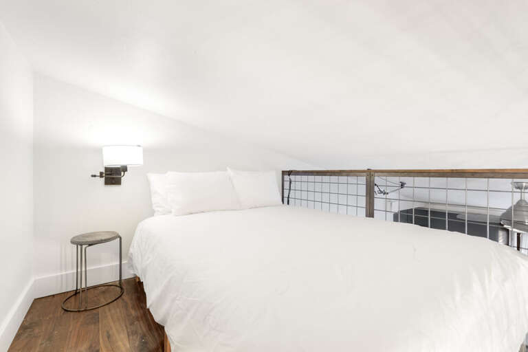 Queen bed overlooks living and dining area.