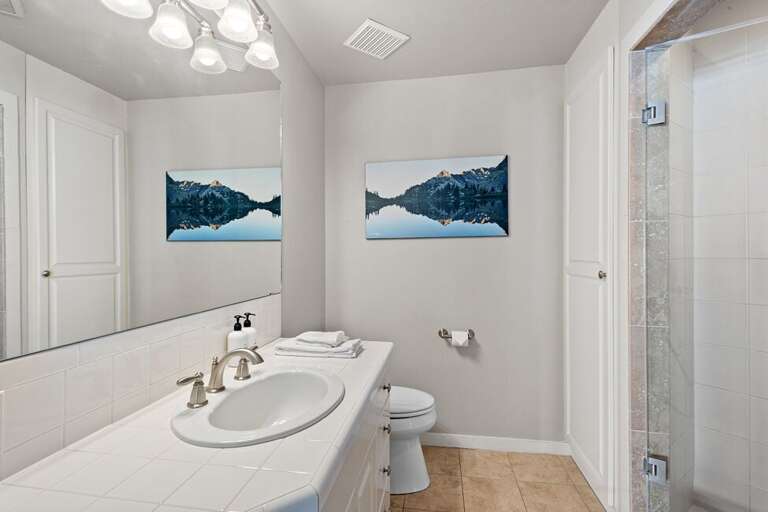 Shared bathroom on the entry level with step in shower and single vanity.