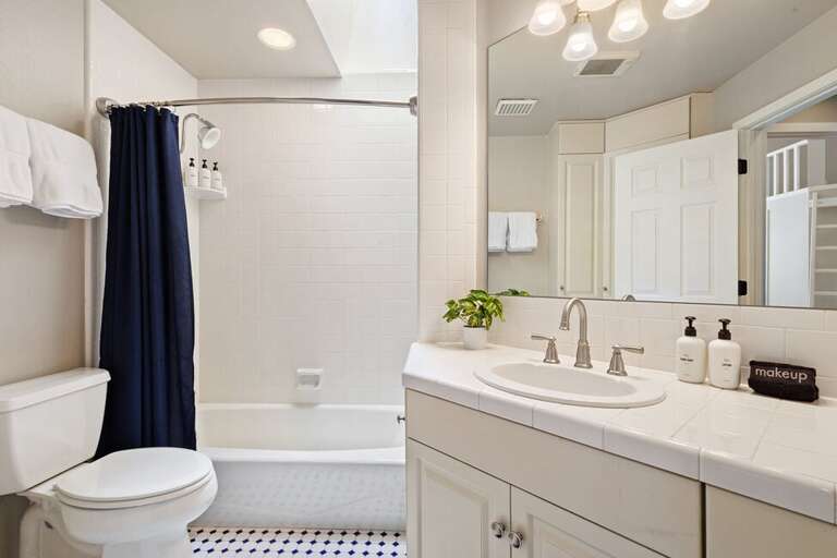 Shared bathroom for guest rooms on top level with tub/shower combo and single vanity