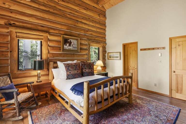 Cozy guest room off the Great Room features a shared full bathroom, queen bed and high ceilings.