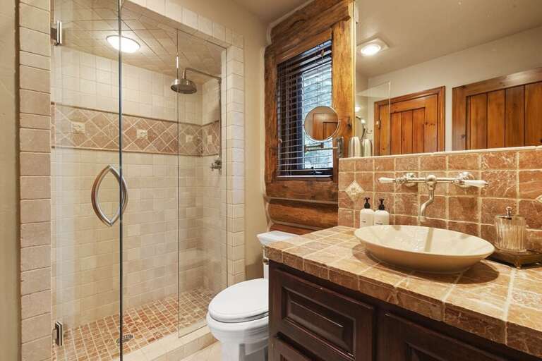 Shared bathroom off the main level features step in shower and single vanity.