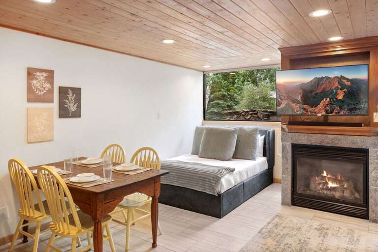 Bright and inviting studio featuring a Queen bed, cozy fireplace, and mountain views through large picture windows.