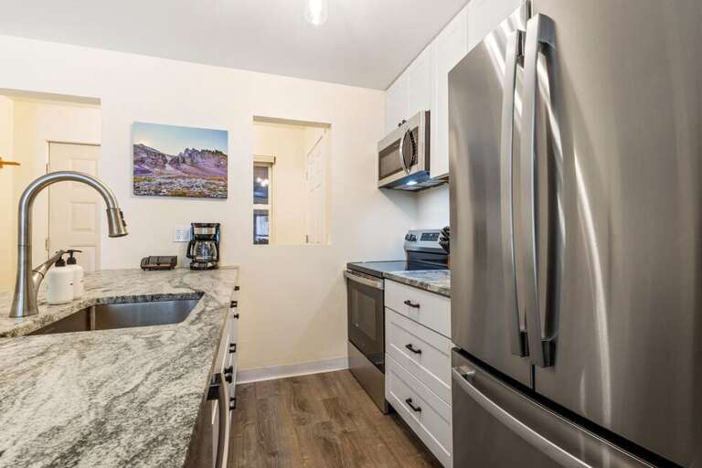 Cook and connect in this newly renovated kitchen with sleek stainless steel appliances and cozy island seating for two.