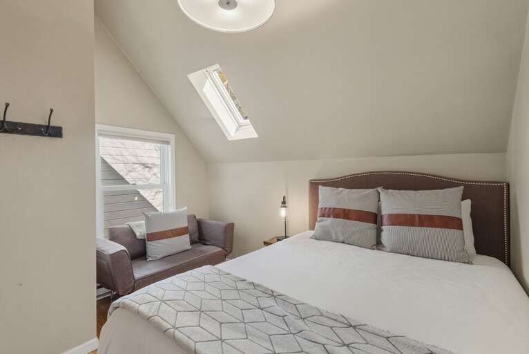 A cozy guest room featuring a comfortable sitting area, and skylights that fill the space with natural light.