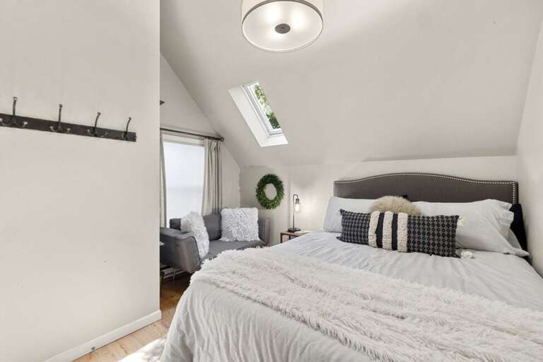 A cozy guest room featuring a comfortable sitting area, and skylights that fill the space with natural light.