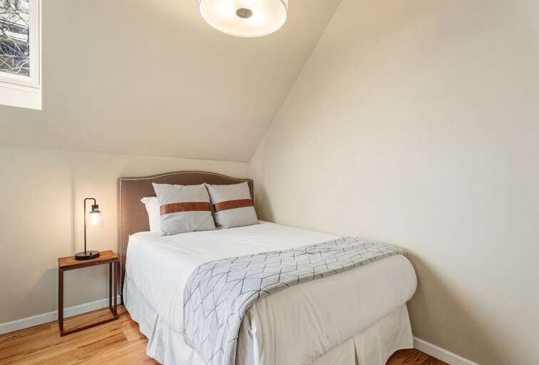 This cute comfortable queen guest bedroom features skylights that allow ample natural light.
