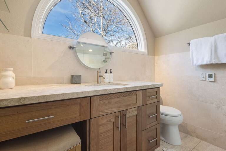 The ensuite offers natural light, a single vanity, and a spa-like, clean atmosphere.