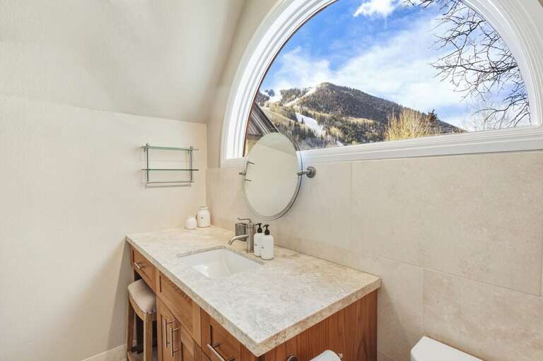 The ensuite offers natural light, a single vanity, and a spa-like, clean atmosphere.