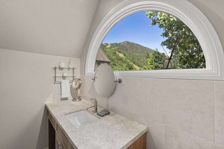 The ensuite offers natural light, a single vanity, and a spa-like, clean atmosphere.