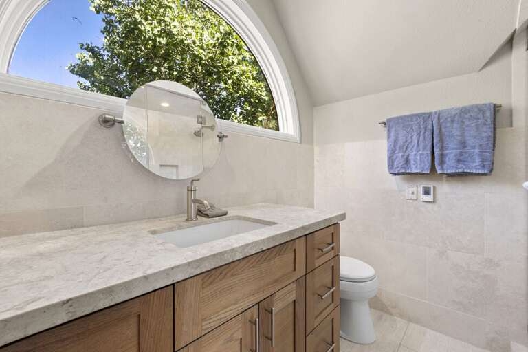 The ensuite offers natural light, a single vanity, and a spa-like, clean atmosphere.