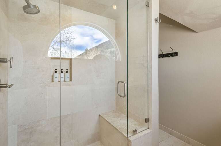 The primary ensuite features a large tiled step-in shower with built-in seating and a single vanity.