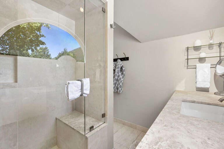 The primary ensuite features a large tiled step-in shower with built-in seating and a single vanity.