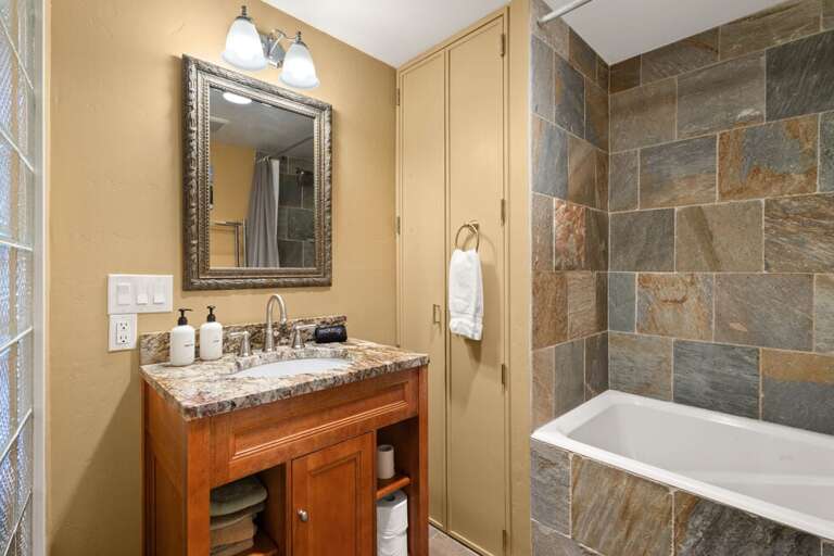 Bathroom with single vanity and integrated soaking tub and shower.