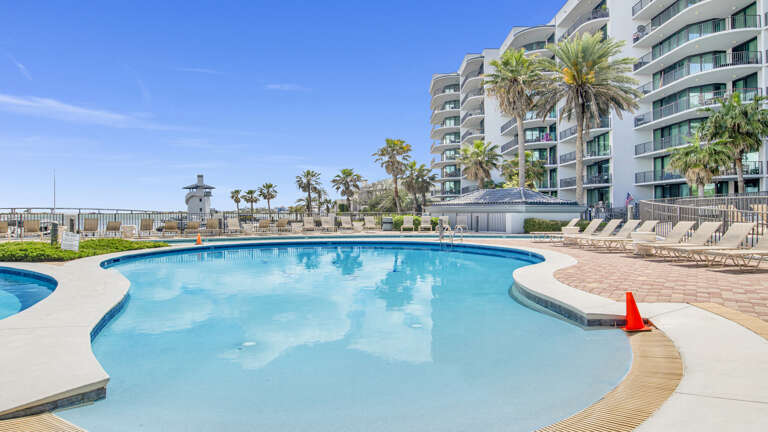 Swimming Pool With Lounge Chairs And Residential Building In The Background