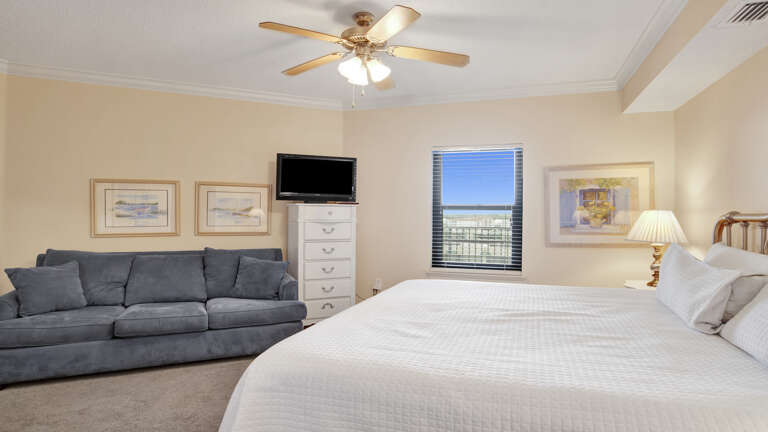 Interior Of A Bedroom With A Bed, Couch, And Ceiling Fan