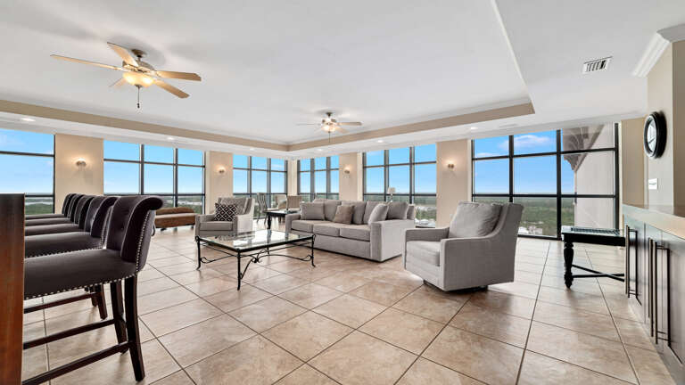 Spacious Interior Living Area With Tiled Floor, Furniture, And Large Windows