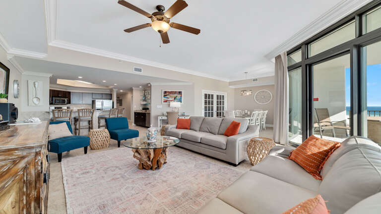 Bright Living Space With Sofas, Kitchen, And Balcony Access