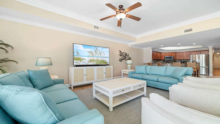 Spacious Living Area With Sofas, TV, Ceiling Fan, And Kitchen