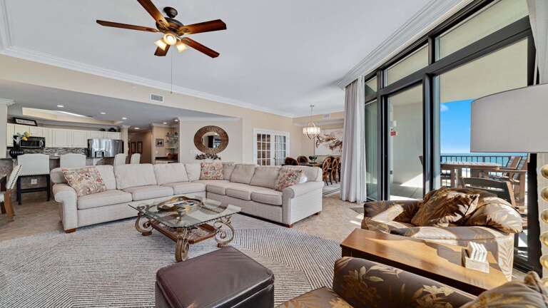 Interior Living Space With Sofas, Coffee Table, Ceiling Fan, And Sliding Doors To Balcony