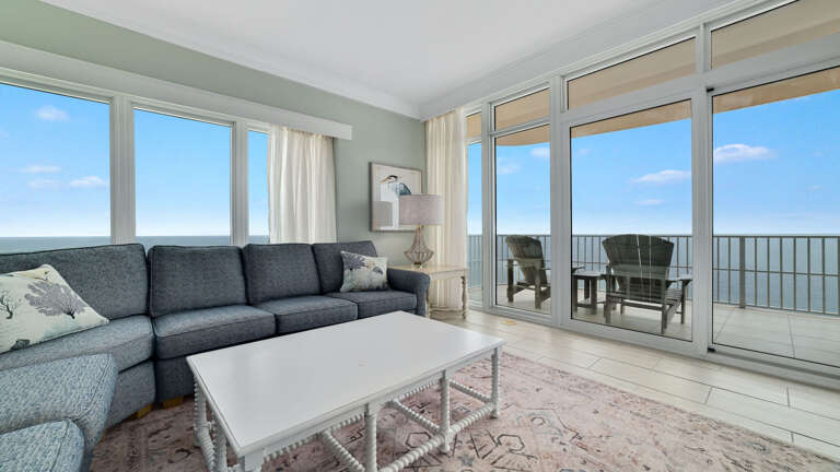 Living Room Interior With Sectional Sofa, Coffee Table, And Balcony Overlooking The Sea