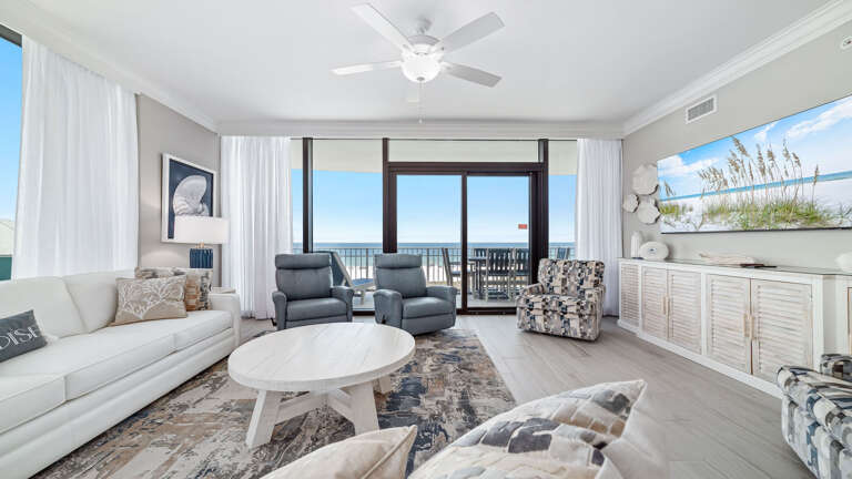 Seaside Living Space Leading To Sunlit Balcony, Featuring Neat Navy Chairs And Beige Blinds