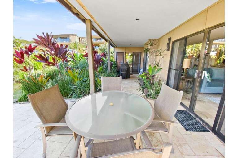 Glass Table And Chairs On A Tiled Terrace With Lush Foliage