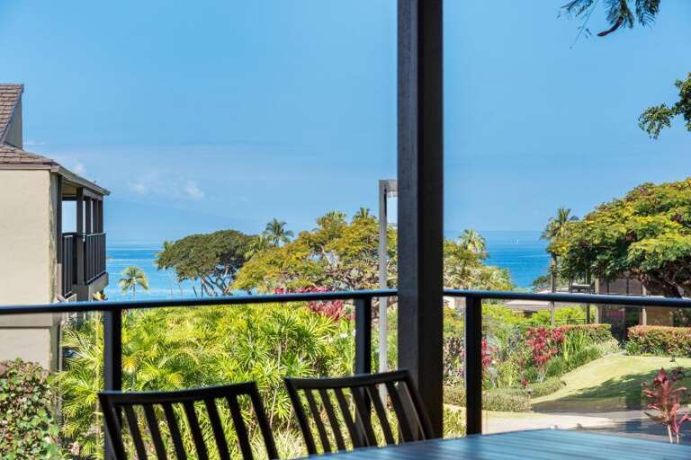 Seaside Scenery From A Shaded Balcony In A Vacation Rental, Lush Landscape Leading To Blue Ocean