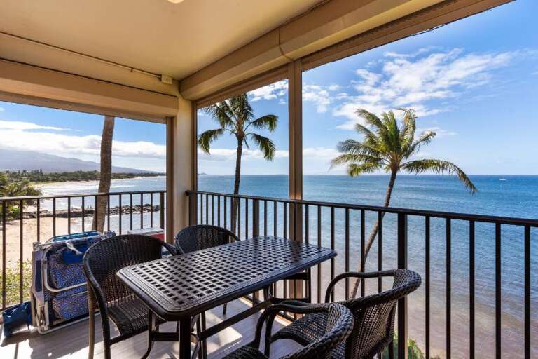 Balcony View Of Beach With Palm Trees And Patio Furniture