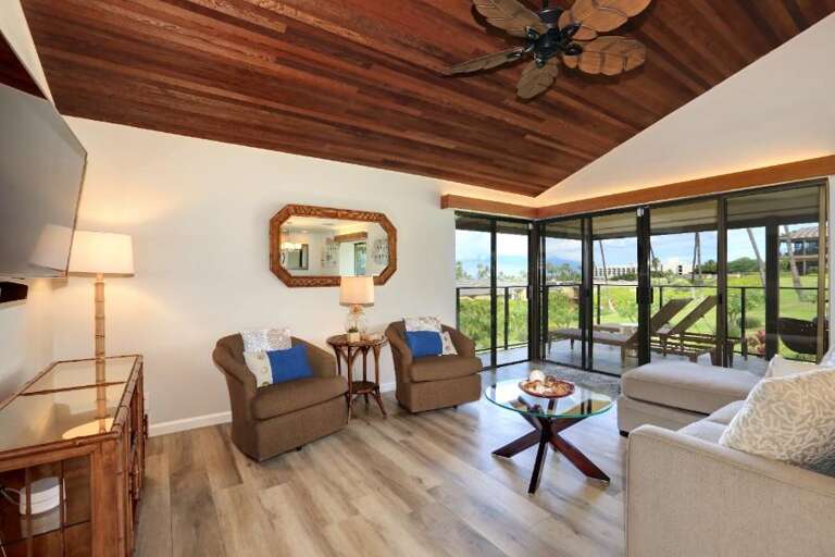 Vacation Rental Living Area With Wooden Ceiling And Large Glass Doors Leading To Balcony