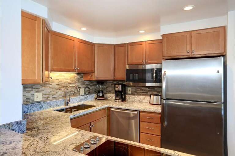 Kitchen In Vacation Rental With Stainless Steel Appliances And Wooden Cabinets