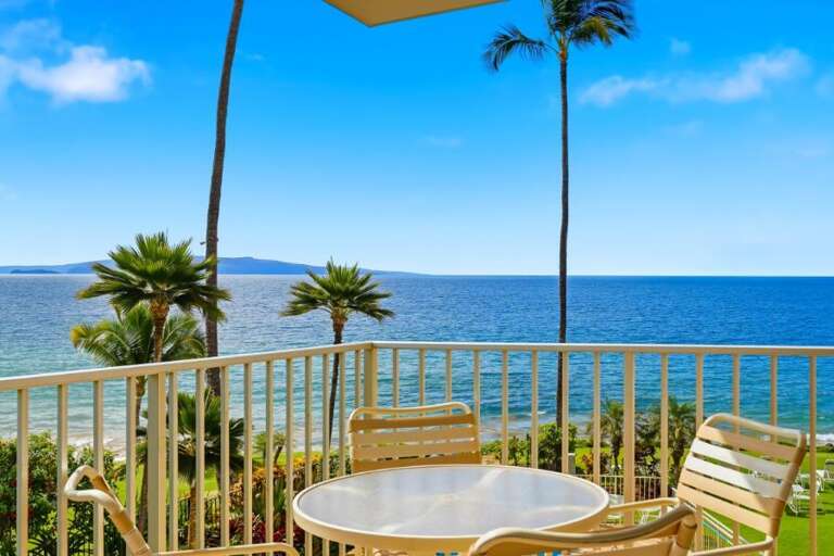 Balcony View With Table And Chairs Overlooking Palm Trees And Blue Sea